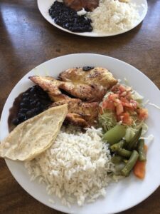 Assiette remplie de riz, poulet, haricots noirs et légumes verts | itinerares