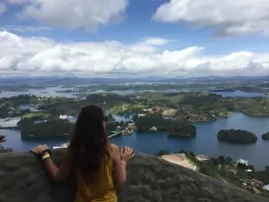 Femme de dos devant un paysage de petites îles sur un lac | itinerares