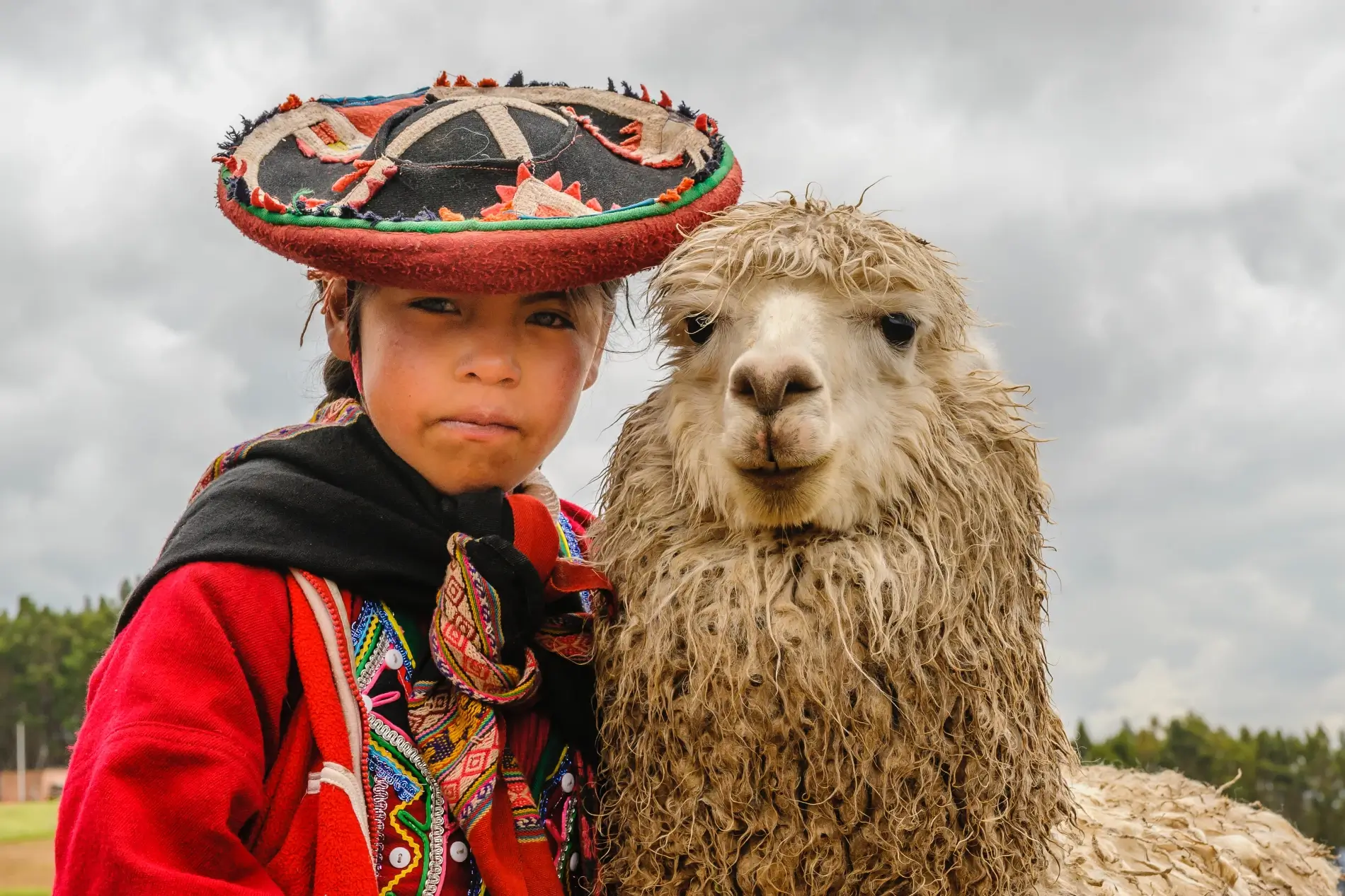 Petite fille péruvienne costumée et son lama | itinerares