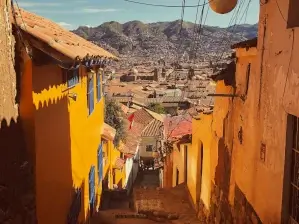 Ruelle colorée aux maisons oranges en descente avec vue sur les montagnes | itinerares