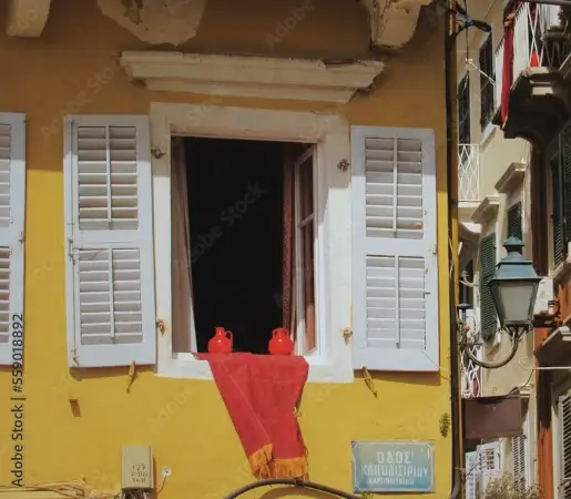 maison jaune ayant une fenêtre ouverte sur laquelle repose deux pots en argile rouge | itinerares