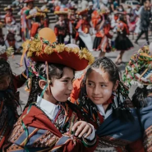 2 petites filles péruviennes costumées discutent au milieu d'une foule en fête | itinerares